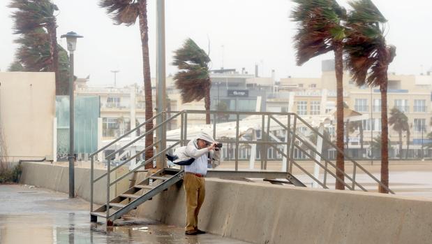 Imagen de un hombre fotografiando el temporal en la playa de Valencia