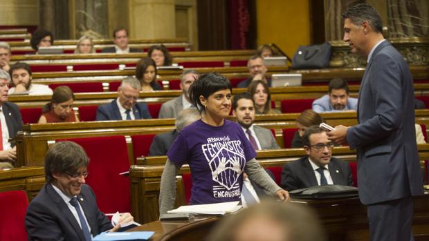 La diputada de la CUP, Anna Gabriel, pasa junto a Carles Puigdemont y García Albiol en el Parlament