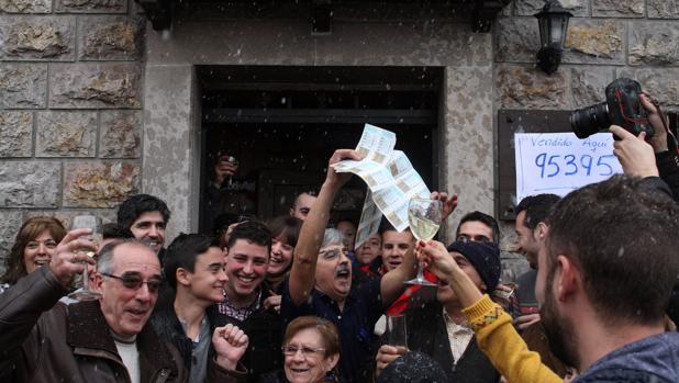 Los agraciados con el tercer premio de la lotería del Niño celebran la suerte delante del mesón que vendió íntegramente el número, en Guardo