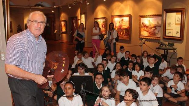 Imagen del pintor Conrado Meseguer, que explica a un colegio de Sueca una de sus exposiciones