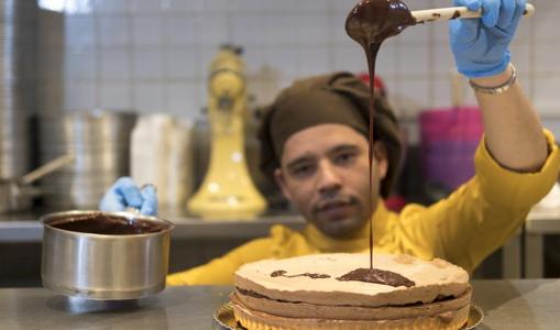 El maestro repostero, cubriendo las capas de la tarta con chocolate fundido