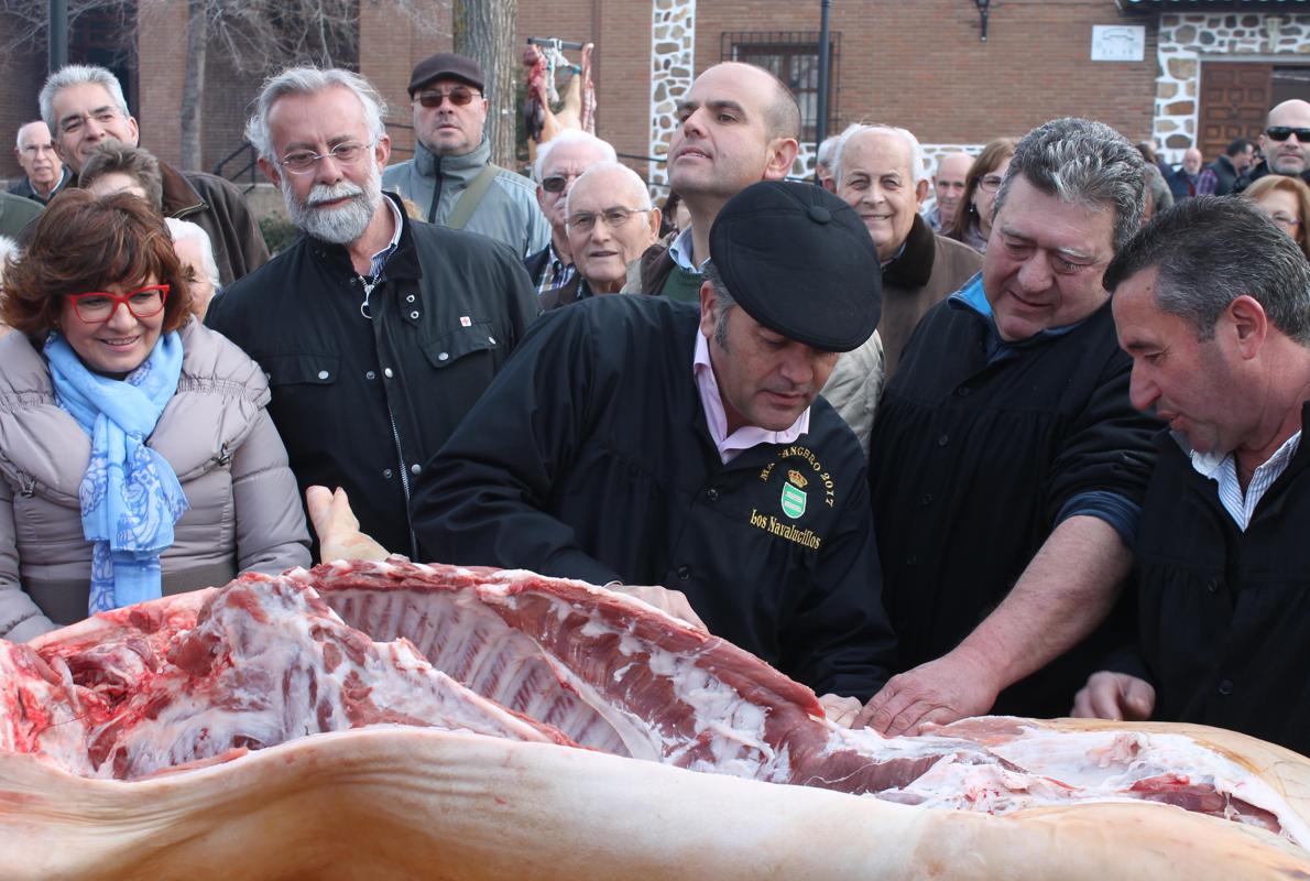 Gregorio corta el cerdo bajo la atenta mirada de Jaime Ramos, Carmen Riolobos y José Ángel Pérez