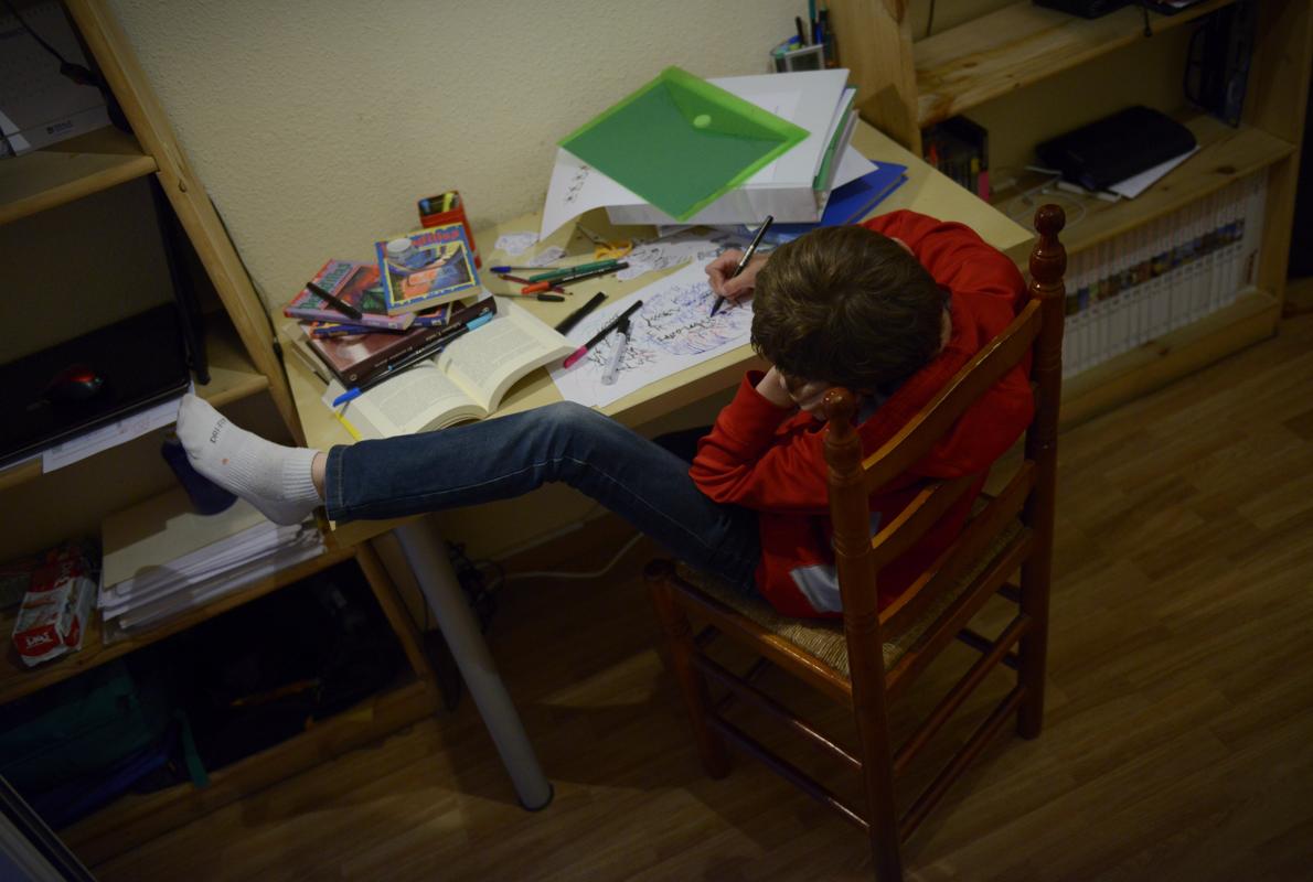 En la imagen, un niño intenta estudiar en una posición imposible