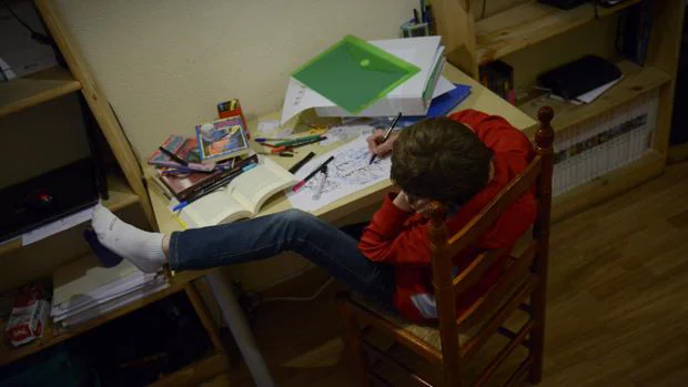 En la imagen, un niño intenta estudiar en una posición imposible