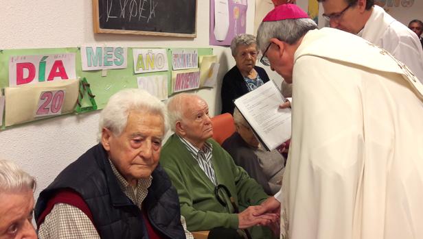 El arzobispo administra el sacramento de la unción de enfermos a uno de los residentes