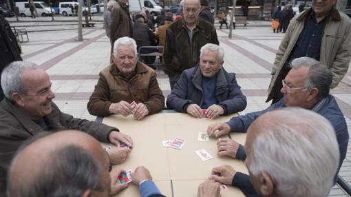 Varios jubilados juegan a las cartas, ayer, en la plaza de Quintana