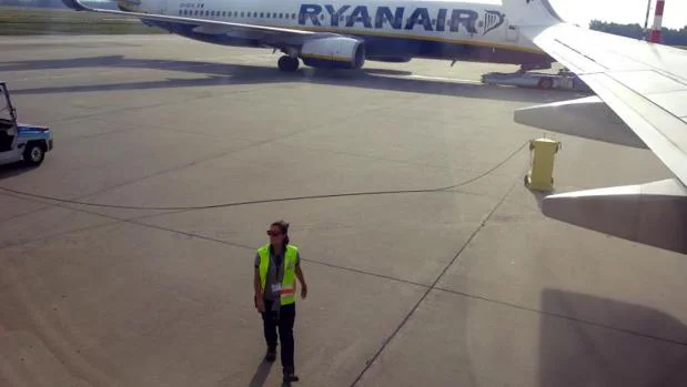 Una trabajadora en el aeropuerto de Alicante-Elche, junto a un avión de Ryanair