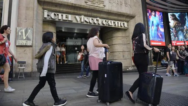 Varios turistas transitan con sus maletas por la Gran Vía de Madrid