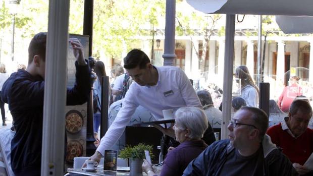 Un camarero sirve bebidas a unos clientes en una terraza