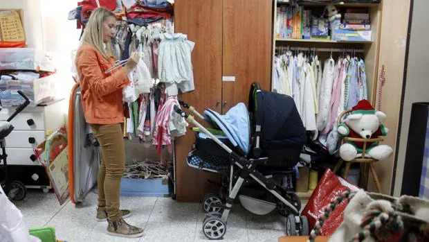 Una voluntaria organiza en el almacén toda la ropa según la edad y el sexo del bebé