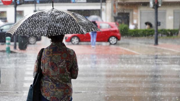 Una mujer se protege de la lluvia en el centro de Valencia