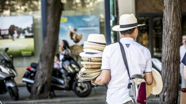Un hombre vende sombreros en el centro de Valencia