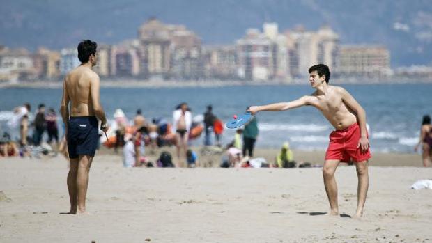 Dos jóvenes juegan a las palas en una playa valenciana
