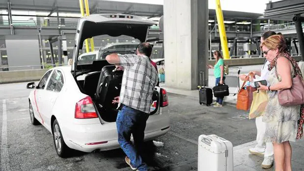Un taxista ayuda a cargar las maletas a unos clientes, ayer, en el aeropuerto de Barajas.