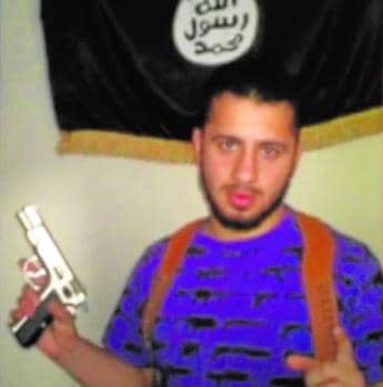 Ahmed Samsam en una fotografía portando una pistola y con la bandera de Daesh al fondo