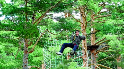 Un hombre disfruta de un recorrido de aventuras entre árboles