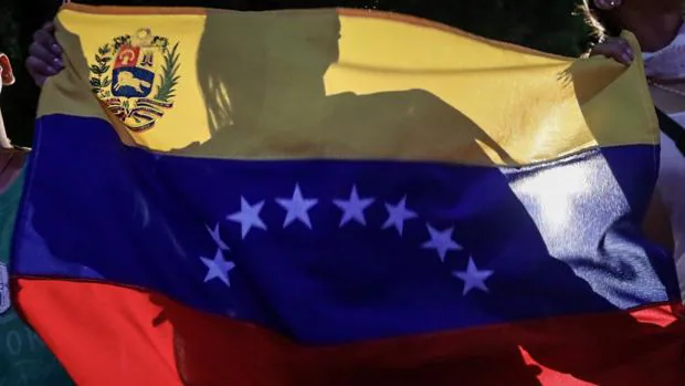 Una mujer tras una bandera venezolana