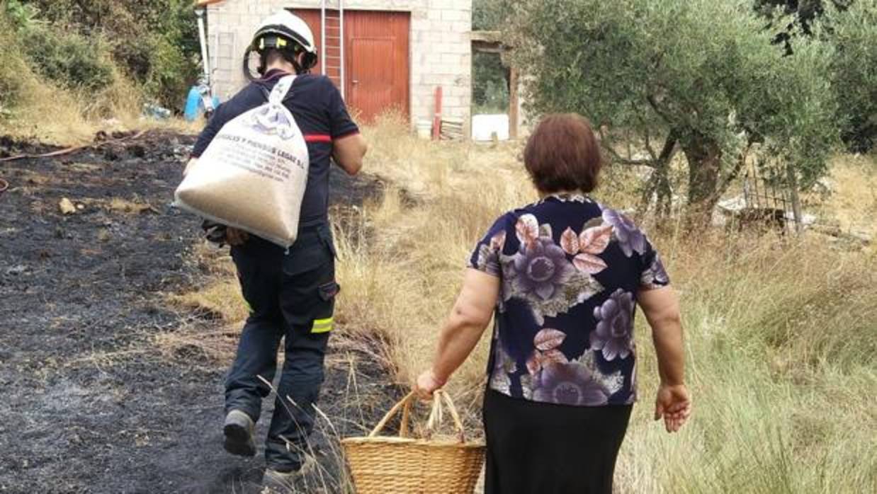Un bombero de la Diputación de Albacete ayuda a una vecina de Los Collados a llevar comida a sus animales