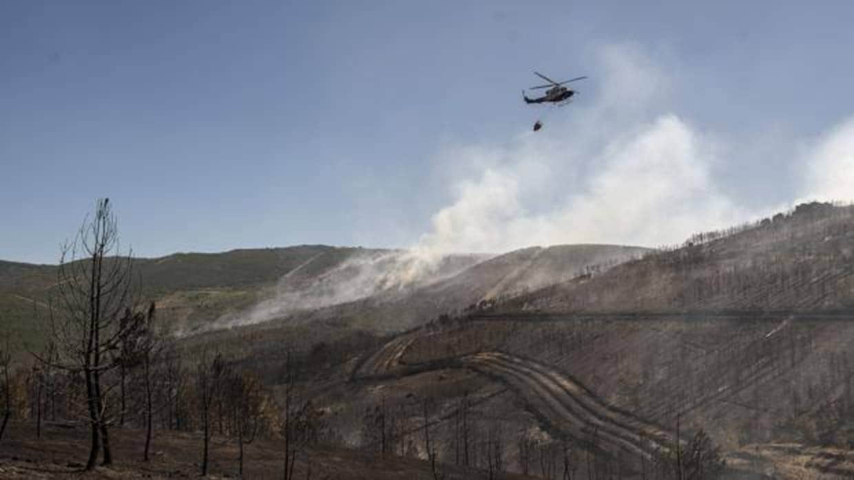 Un helicóotero sobrevuela las zonas calcinadas por las llamas