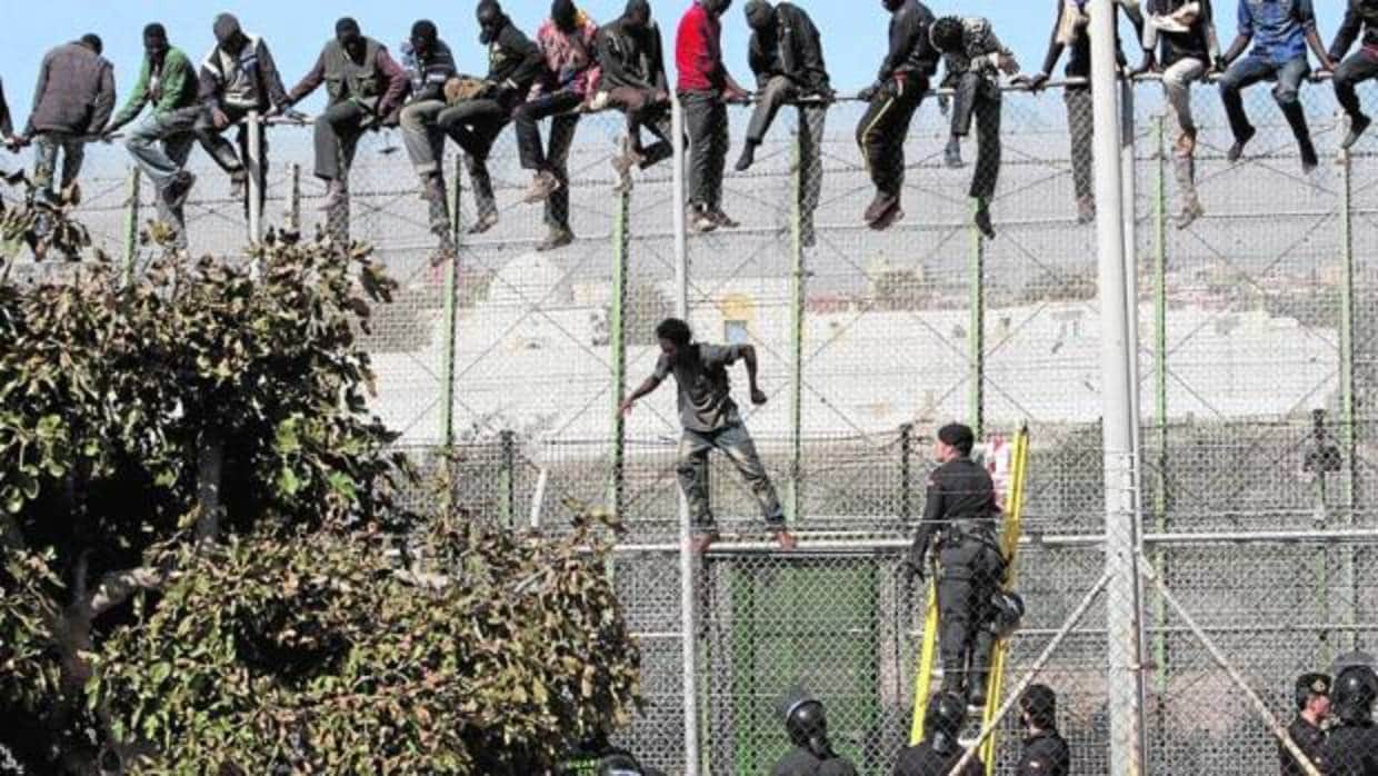 Varios inmigrantes de origen subsahariano encaramados a la valla de Melilla