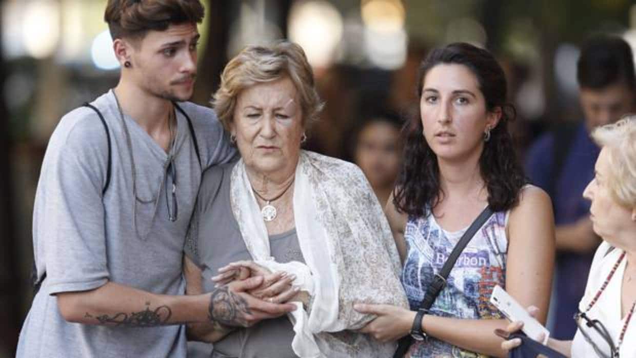 Unos ciudadanos ayudan a uno de los heridos en el atentado de Barcelona