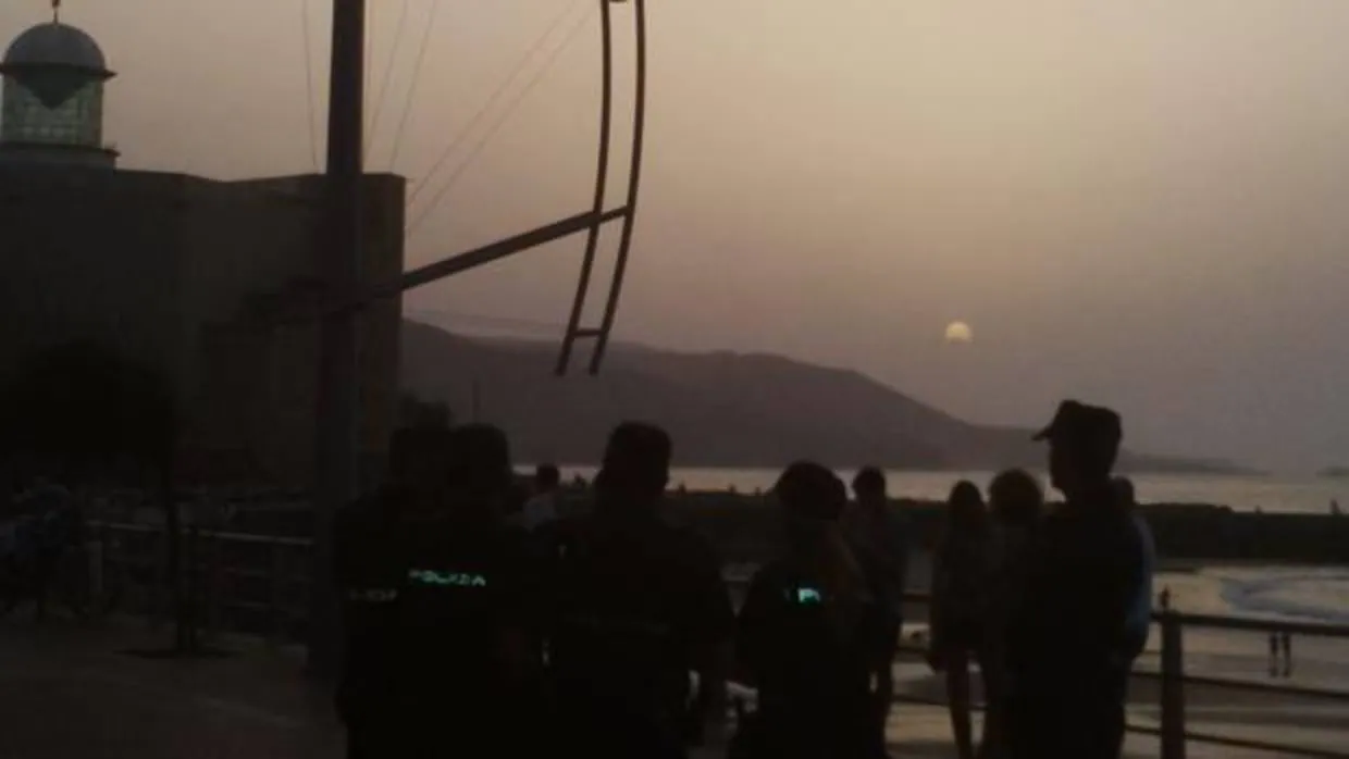 Agentes de Policía, este lunes, cuando se producía el eclipse en Las Canteras, Gran Canaria, afectada de calima