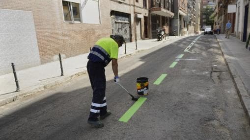 Un operario pinta las plazas de aparcamiento en la calle de Fernando Garrido