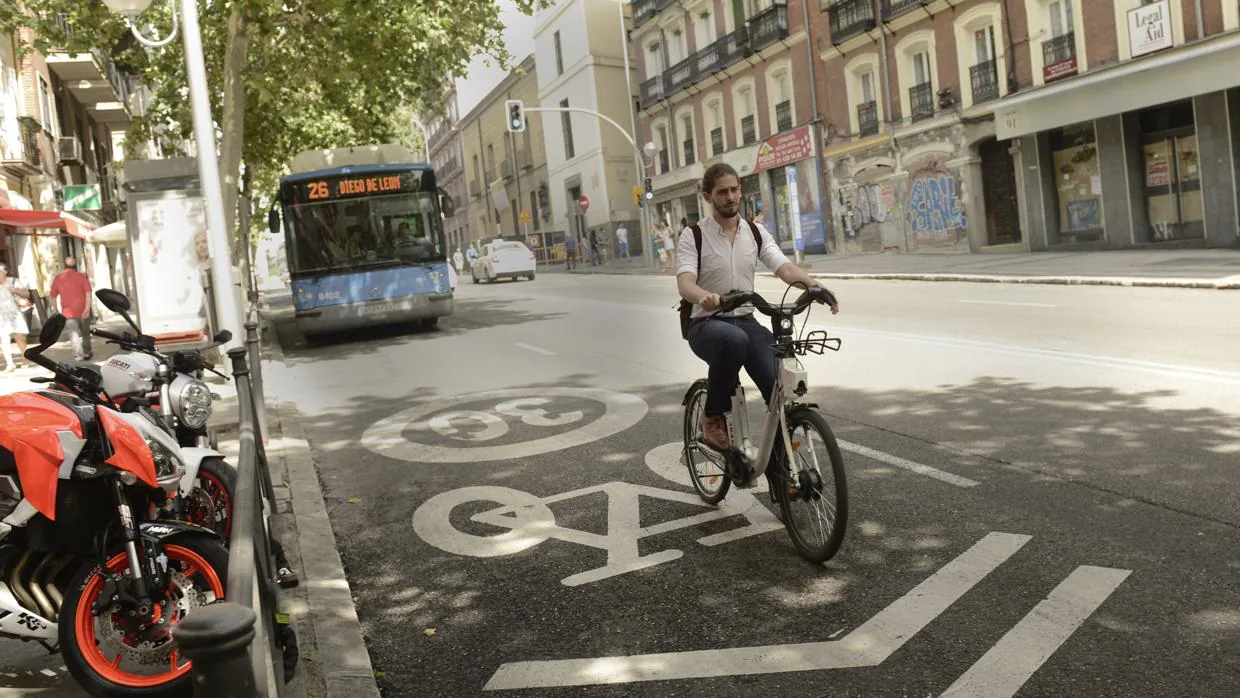 Un ciclista avanza delante de un autobuús, por un ciclocarril 30 de Madrid