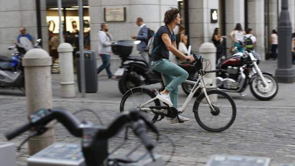 Un usuario de BiciMad circula ante una estación en Madrid