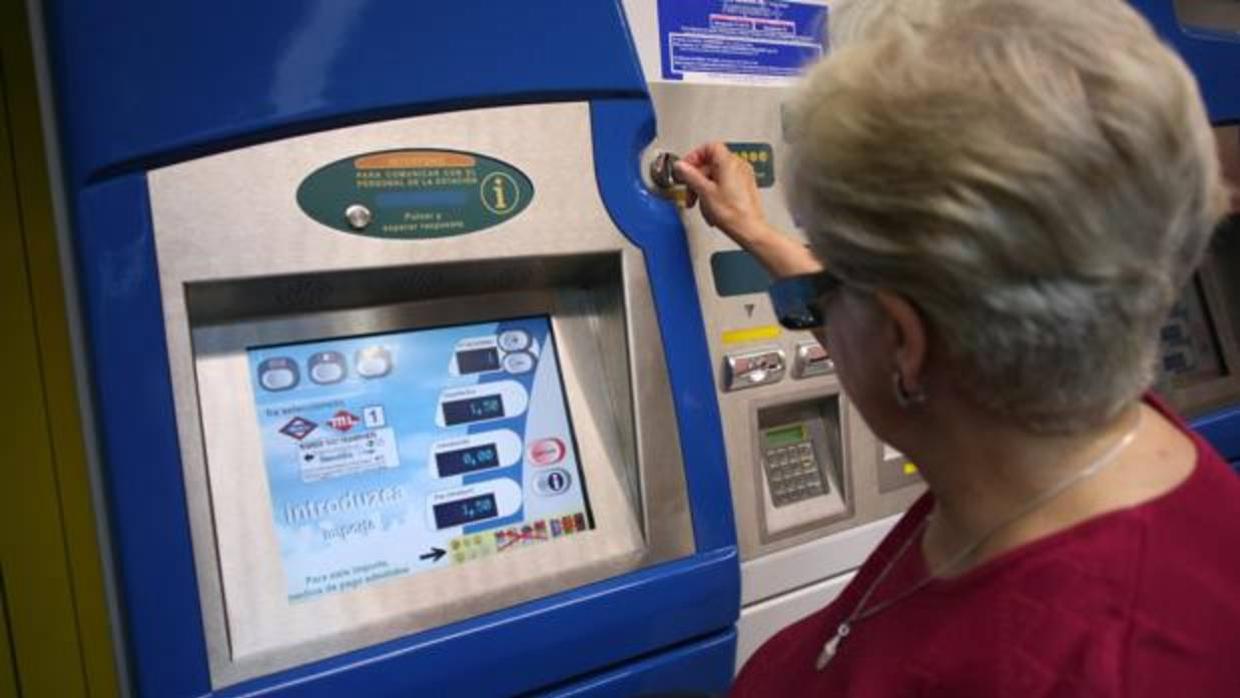 Una pasajera saca un billete de Metro en una máquina expendedora