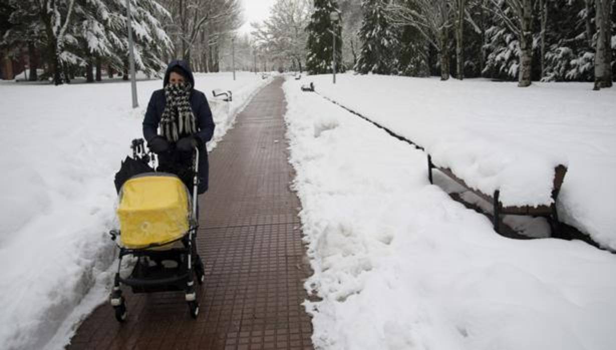 Un mujer pasea con un bebé por uno de los parques nevados de la ciudad de Vitoria