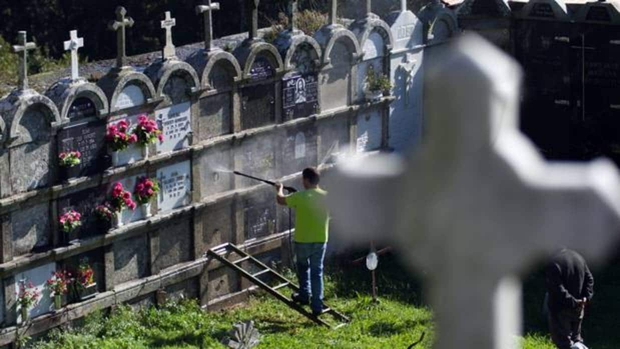 Un operario limpia sepulturas en un cementerio de Galicia
