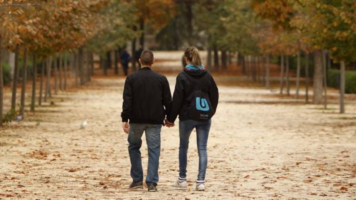 Una pareja de jóvenes pasea por un parque