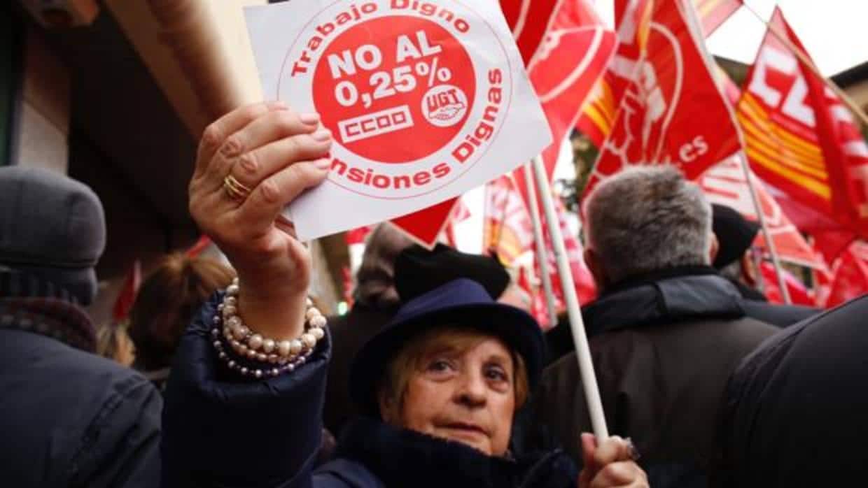 Una manifetante muestra un cartel de protesta contra la revalorización de las pensiones del 0,25%