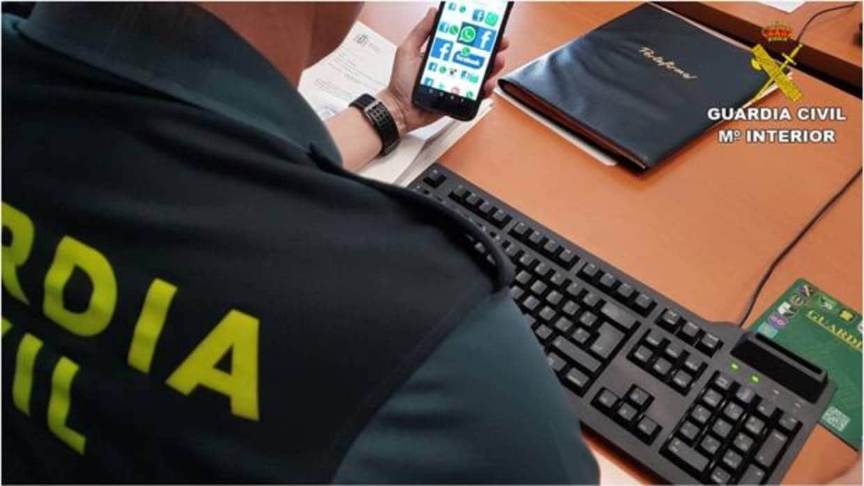 Un agente de la Guardia Civil observa un móvil con aplicaciones de redes sociales