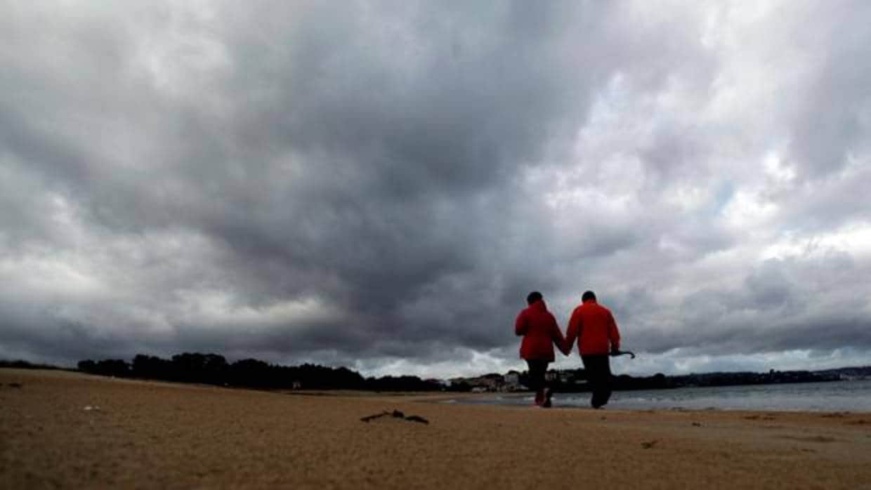 Una pareja caminando este viernes en la playa de Miño antes de la llegada de Félix
