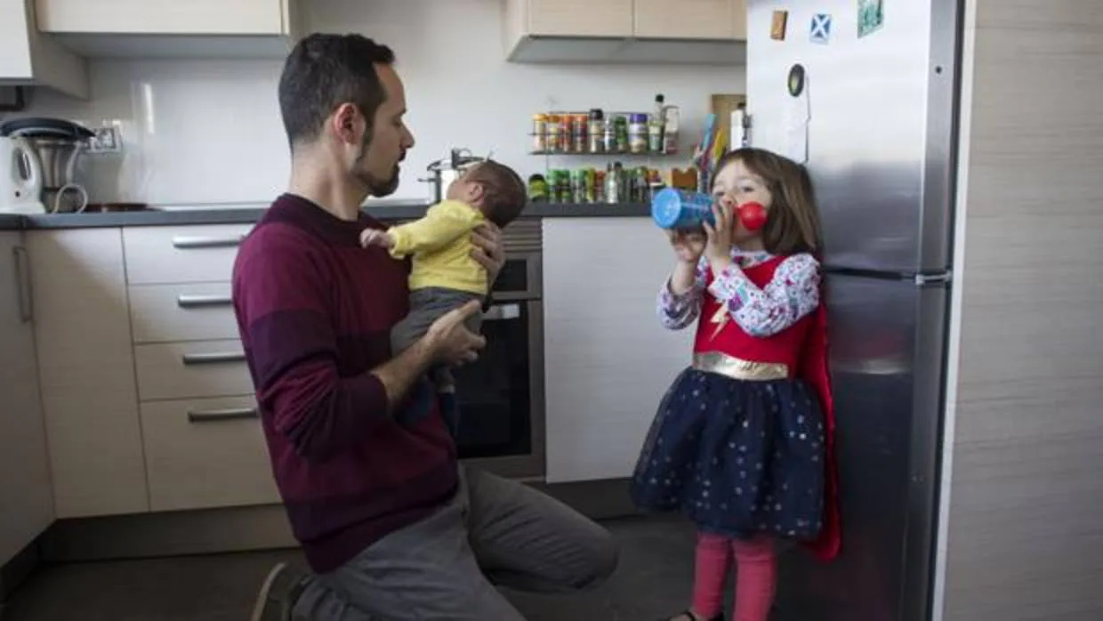 Un padre atiende a sus dos hijos menores en la cocina de su vivienda