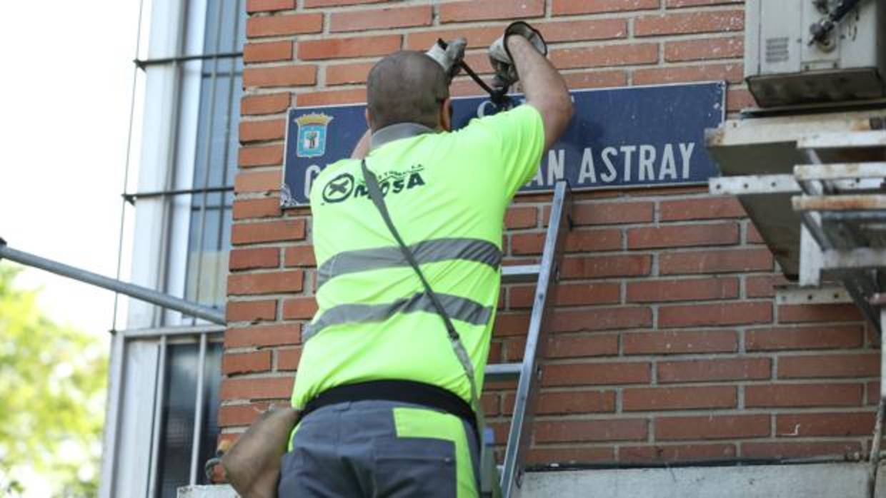 Un operario del Ayuntamiento de Madrid quita la placa de la calle dedicada al general Millán Astray