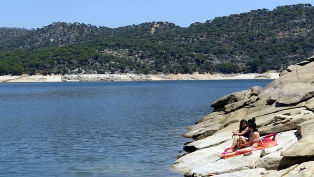 Dos bañistas toman el sol en una orilla del pantano de San Juan