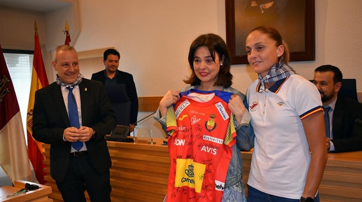 Pilar Zamora recibe de manos de la capitana de la selección de balonmano la camiseta del equipo firmada