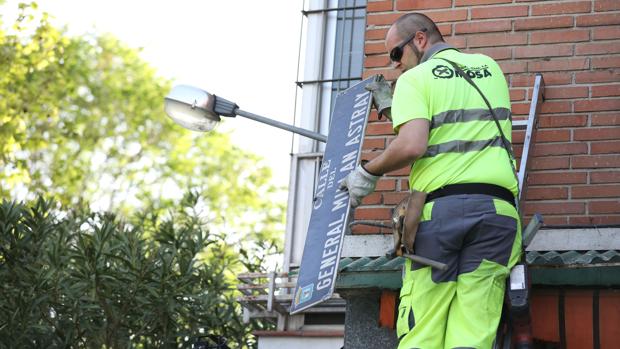 Un operario retira la placa del General Millán-Astray