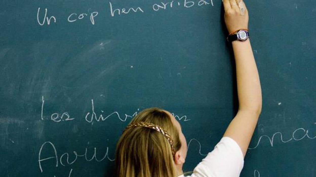 Una niña escribiendo en catalán en la pizarra de su clase