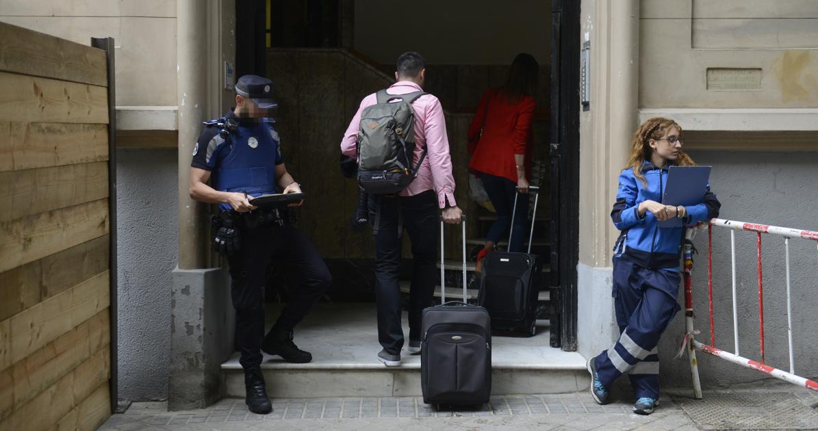 Agentes municipales custodian la entrada del inmueble mientras los vecinos entran para poder recoger sus pertenencias