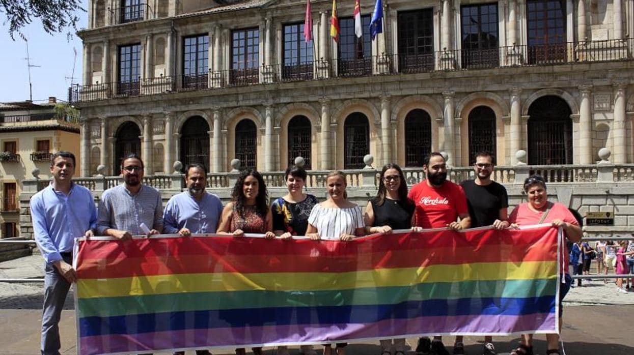 Concejales de PSOE, Ganemos y Ciudadanos y miembros de la asociación Bolo-Bolo posan con la bandera arcoíris en la plaza del Ayuntamiento de Toledo