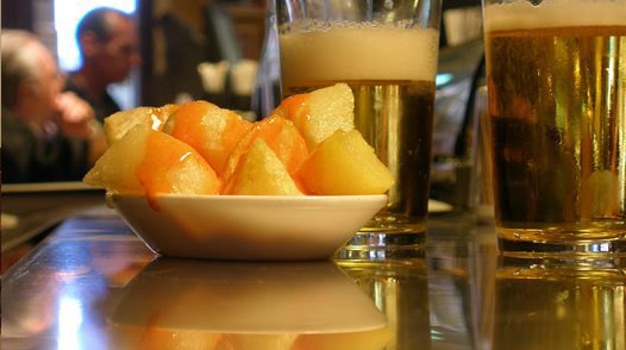 Dos cañas en la barra de un bar junto a una tapa de patatas