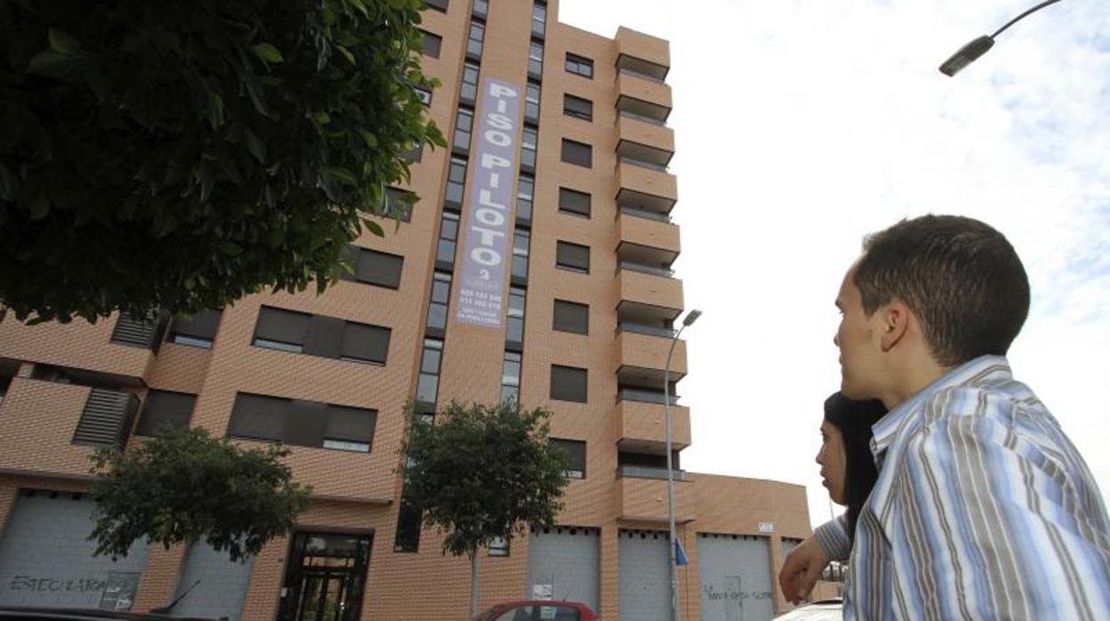 Una pareja mira el cartel de unos pisos en venta en Alicante