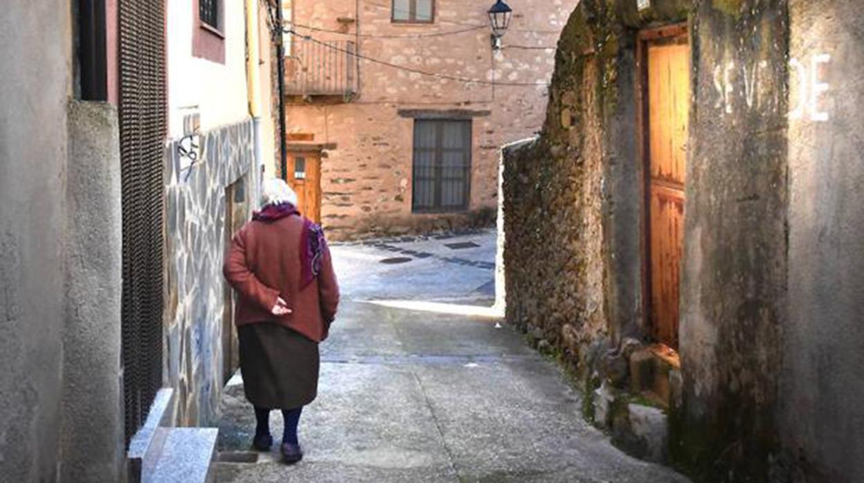 Una anciana anda por la calle vacia de un pueblo