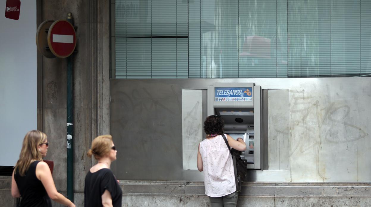 Una mujer saca dinero de un cajero automático