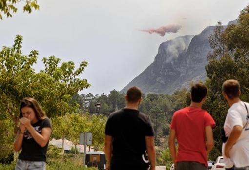 Residentes en zonas próximas al fuego observan los trabajos de extinción