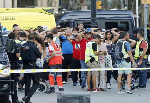 Un grupo de gente con los brazos en alto ante el despliegue policial en el lugar del atentado